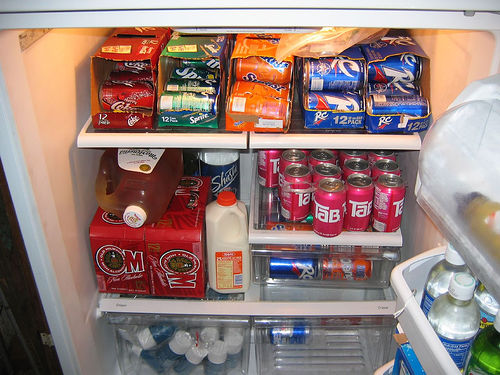 A refrigerator packed with cans of soda.