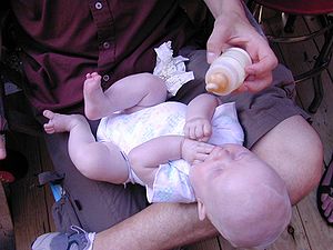 A baby having milk from a bottle.